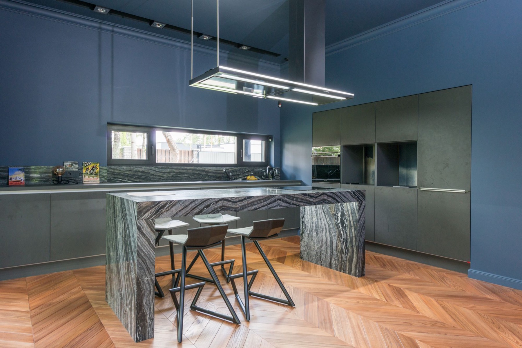 A kitchen lit by a long linear pendant over the island, with the rest of the room on separate downlight circuits